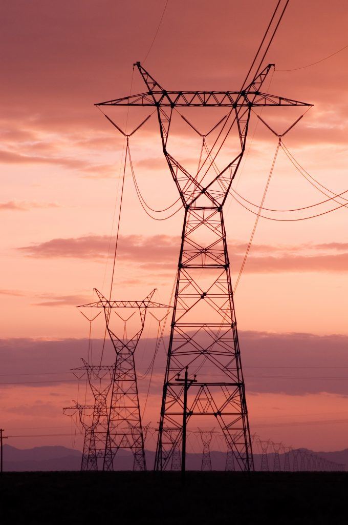 A photo of transmission lines during a beautiful purple and salmon-colored sunset.